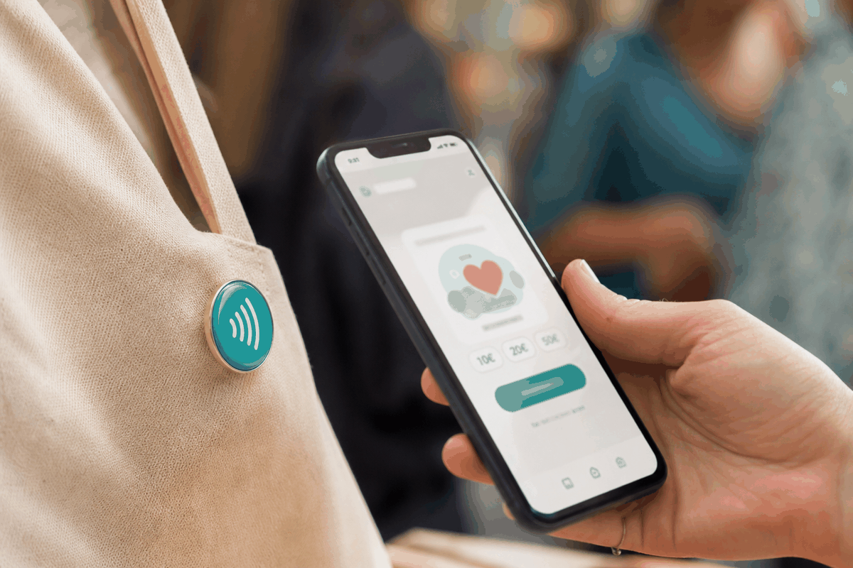 Smartphone scannant un pin's connecté NFC et affichant une page de don pour une association